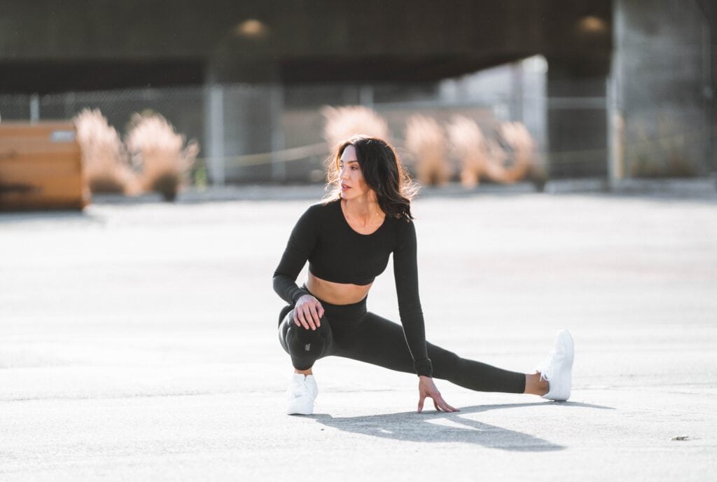 A woman in workout attire stretching outdoors, demonstrating the importance of flexibility and outdoor physical activity in a healthy lifestyle.