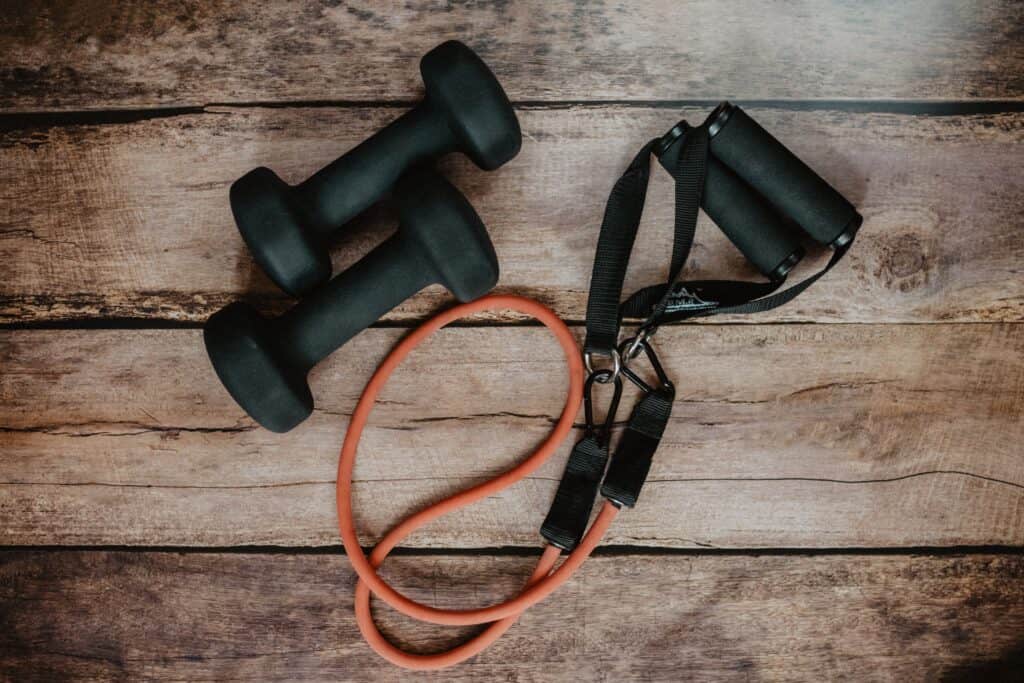 Free weights and a stretch band neatly arranged on the floor, showcasing essential fitness equipment for strength training and flexibility exercises.