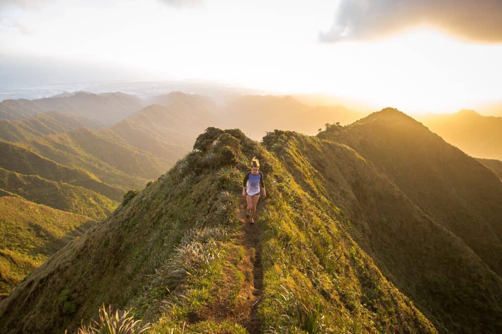 An adventurous woman hiking on lush green hills, surrounded by vibrant nature and breathtaking landscapes. The serene scene captures the joy of outdoor activity, promoting a healthy and active lifestyle immersed in nature.