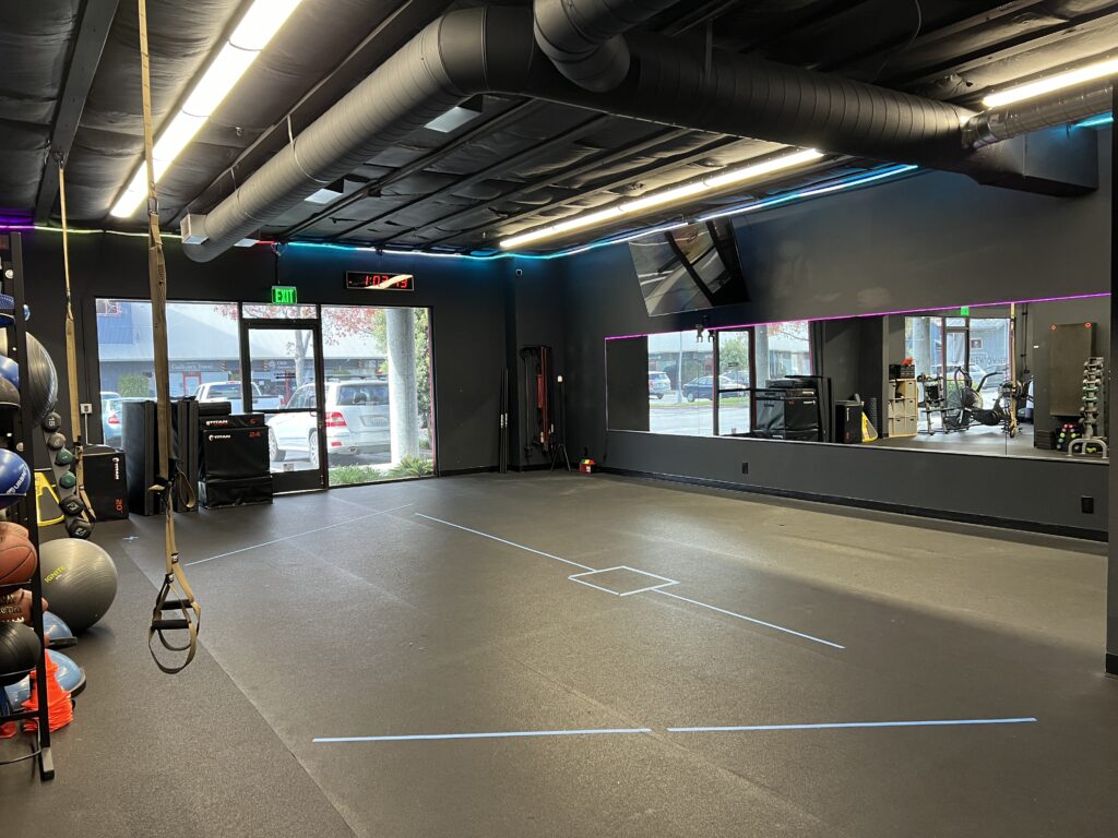 Well-equipped rental studio featuring floor mats, free weights, and resistance bands in a vibrant gym setting.