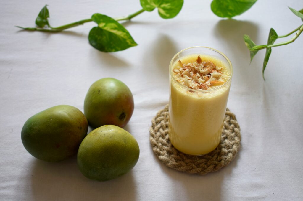 Nutritious protein shake in a clear glass, featuring a smooth blend of protein powder, milk, and fruits. A shaker bottle and ingredients are visible in the background.