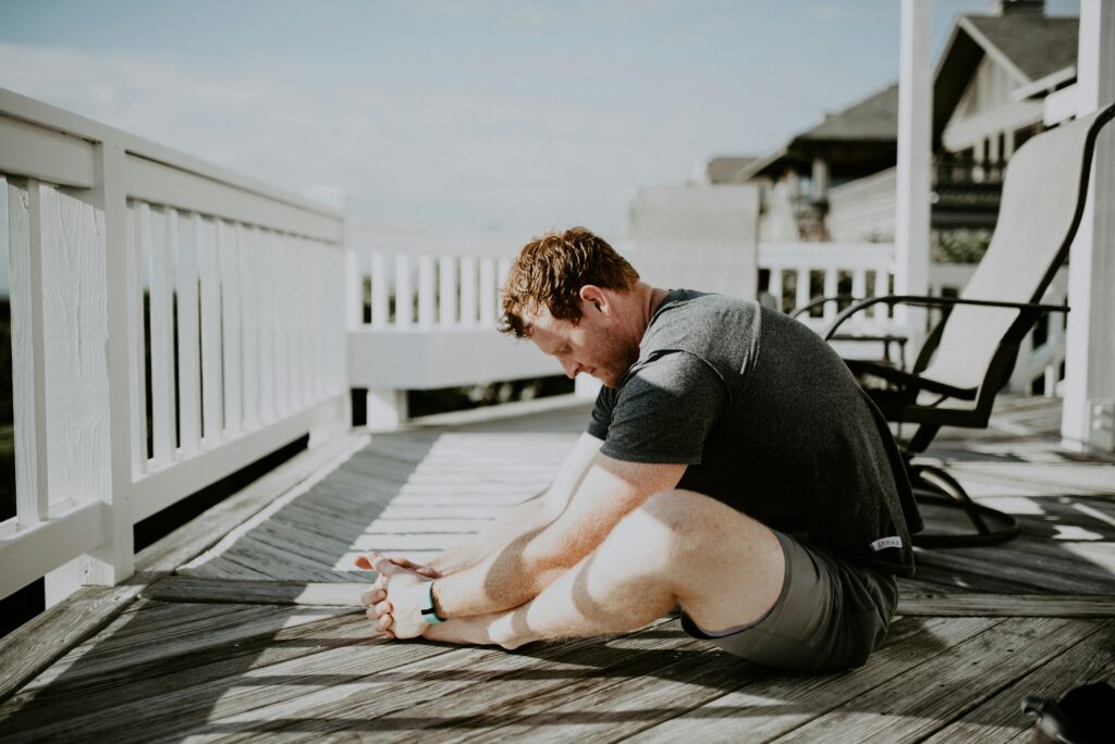 A man in workout attire stretching post-exercise on a mat, emphasizing cool-down and muscle relaxation. He performs various stretches to aid recovery and enhance flexibility.