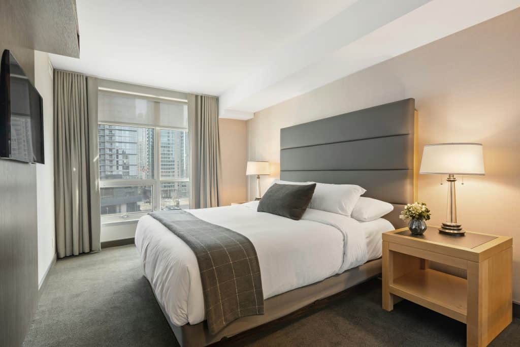 Modern hotel room with a king-sized bed, stylish decor, a large window offering a scenic view, and a well-organized workspace.