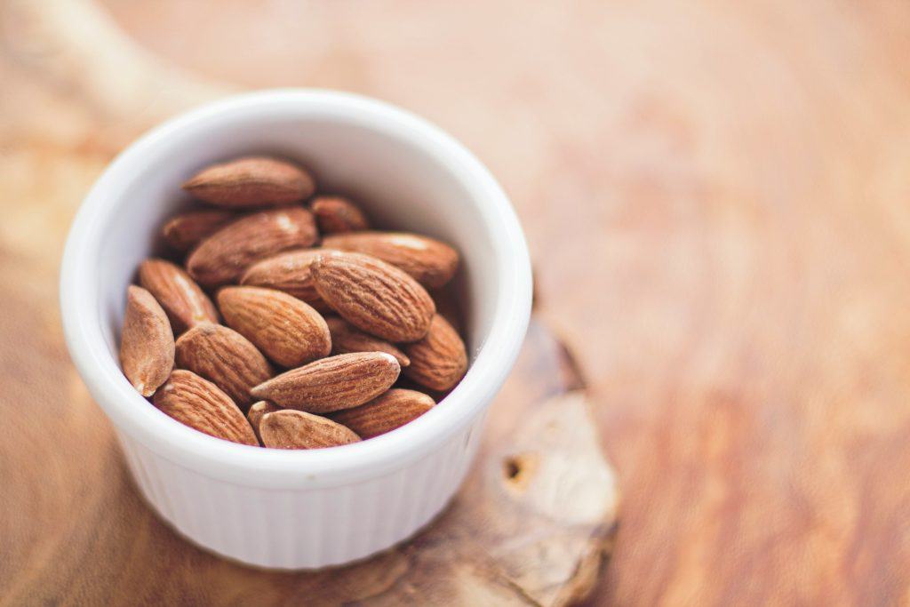 Ramekin filled with raw almonds, showcasing their natural texture and color.