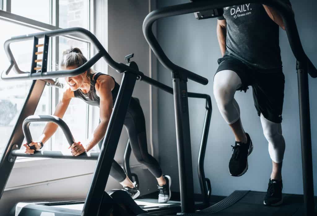 Two people working out side by side on treadmills at the gym.