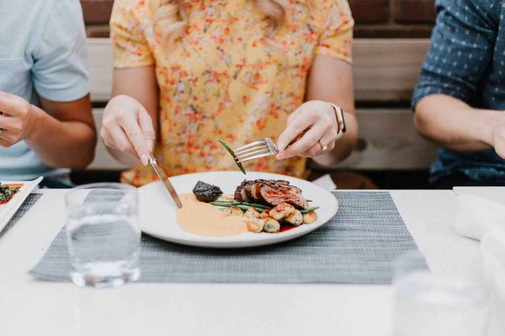 A woman mindfully eating her dinner, savoring each bite with a calm and focused expression, highlighting the practice of mindfulness in her eating habits.