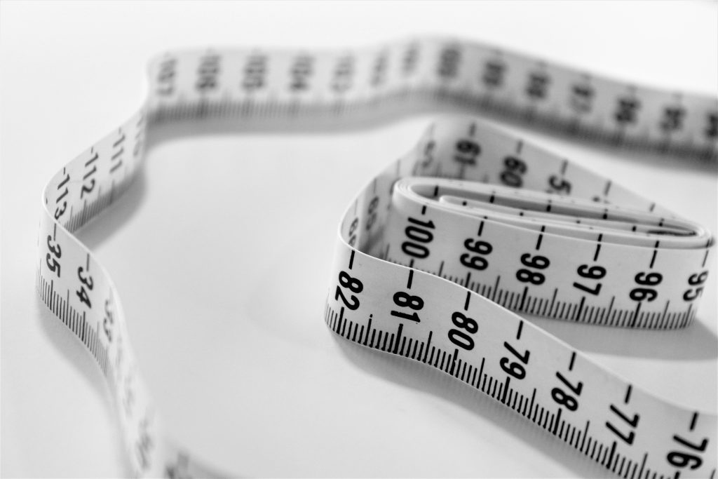 Close-up of a tape measure wrapped around a person's waist, used for tracking body measurements and fitness progress.