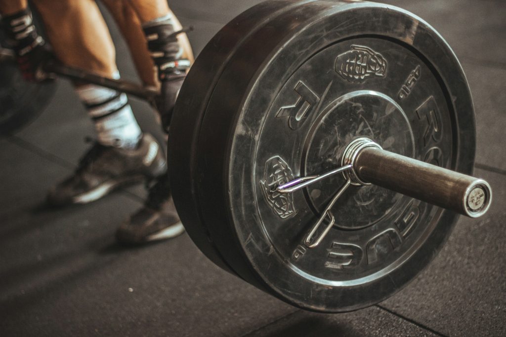 Close-up of heavy weight plates stacked on a barbell in a gym, ready for lifting. The plates rest on a dark gym floor, emphasizing strength training and the intensity of weightlifting workouts.