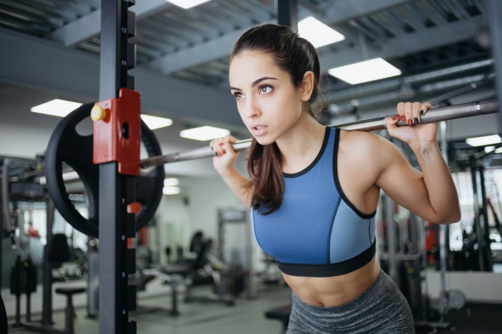 A woman performing a deadlift in a gym setting, emphasizing proper form and determination.