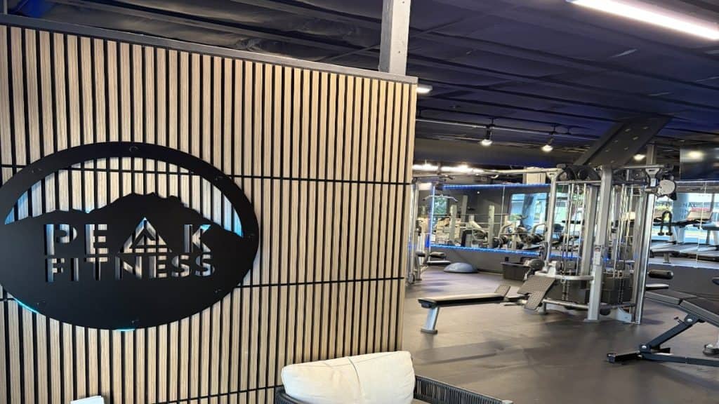 Peak Fitness SLO logo wall with gym floor and strength training equipment in San Luis Obispo