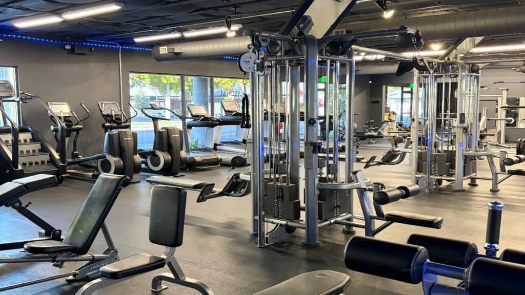 Cable machines and cardio equipment with natural light at Peak Fitness gym in San Luis Obispo