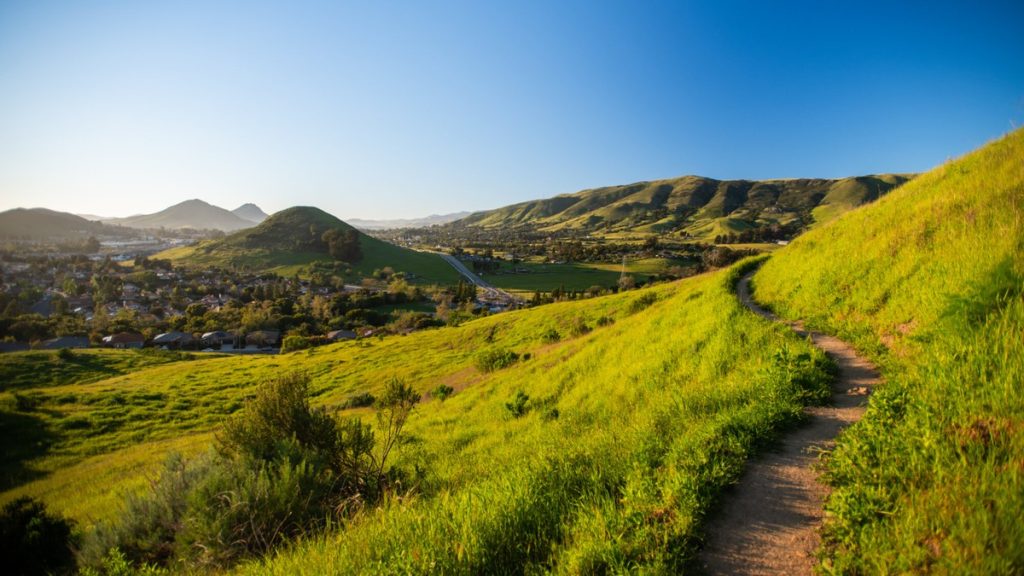 Winding trail through green hillside on Cerro San Luis with the Morros visible in the distance, San Luis Obispo