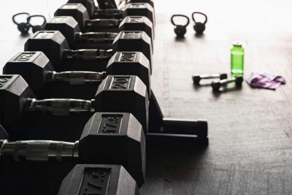 Close-up of a dumbbell rack with kettlebells and workout gear, representing strength training equipment at the gym