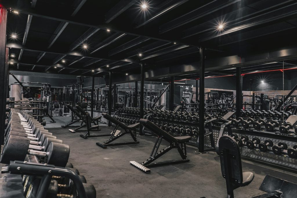 Fully equipped gym floor with dumbbell racks and weight benches for strength training at Peak Fitness SLO