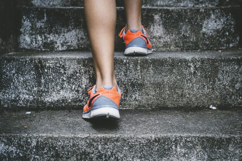 Runner climbing outdoor stairs in athletic shoes, representing sustained physical effort and the importance of staying hydrated