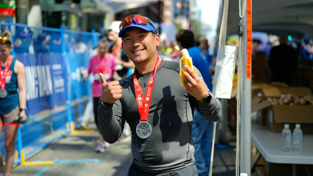 Endurance athlete giving a thumbs up and eating a banana after finishing a race