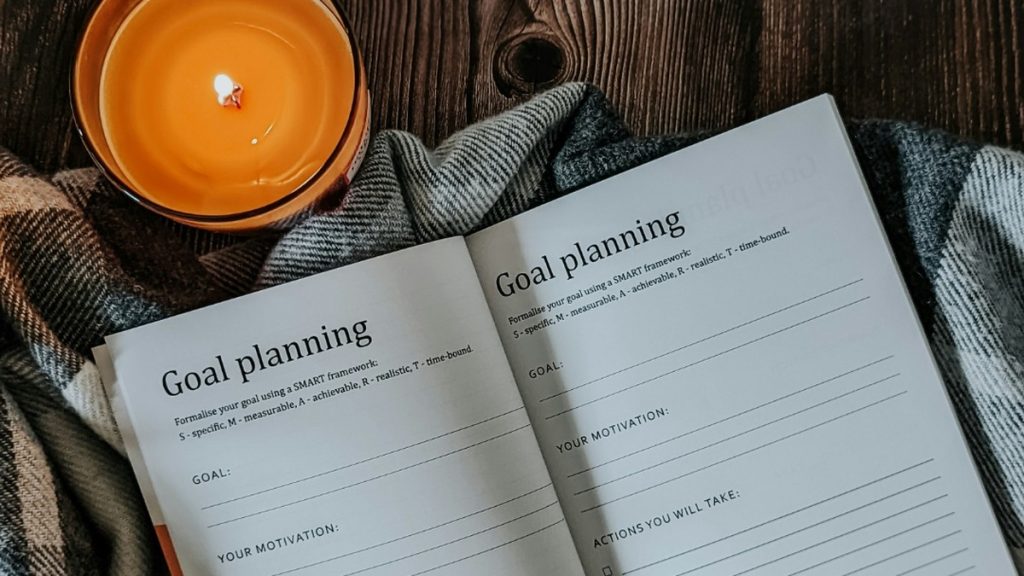 Open monthly goals planner with handwritten fitness goals and a coffee cup on top