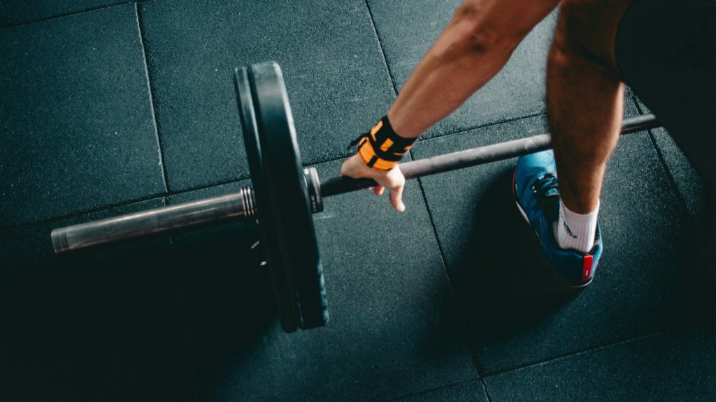 Close-up of hands gripping a loaded barbell during a deadlift at a gym