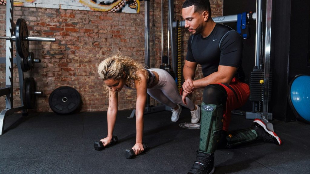 Personal trainer coaching a client through an exercise on the gym flo