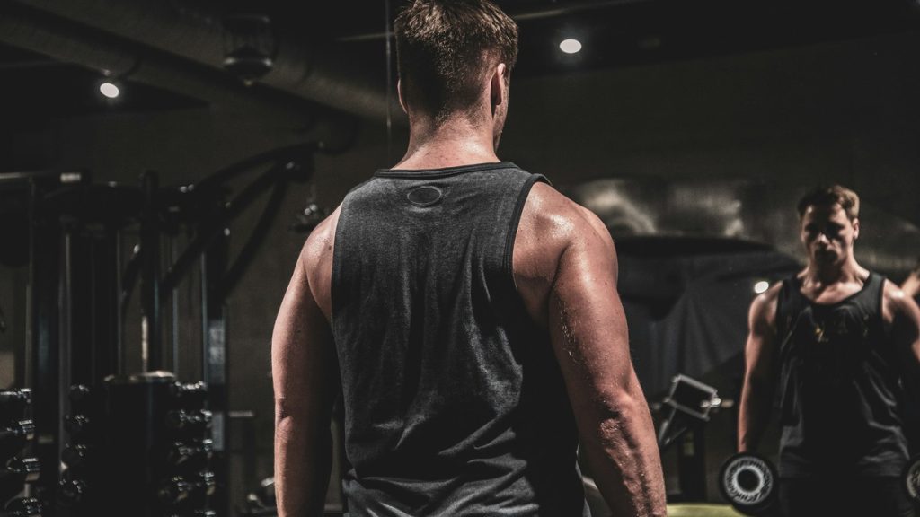 Two young men lifting weights together in a moody gym setting
