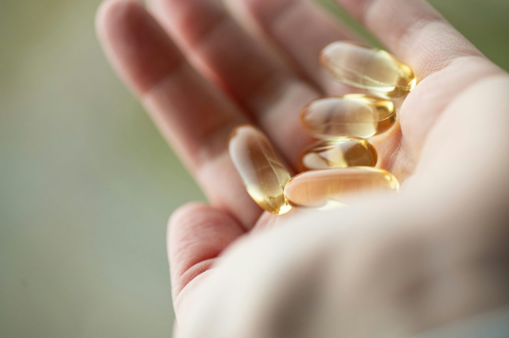 Golden omega-3 fish oil softgel capsules in someone's hand