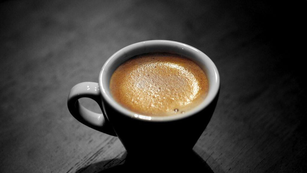 Freshly pulled espresso in a dark ceramic cup on a wooden table