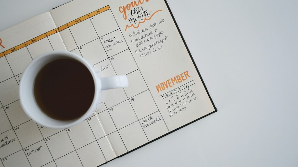 November planner with monthly goals and a cup of coffee for scheduling holiday workouts