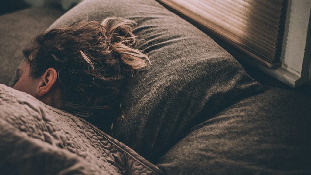 Woman sleeping under soft blankets to recover during the busy holiday season