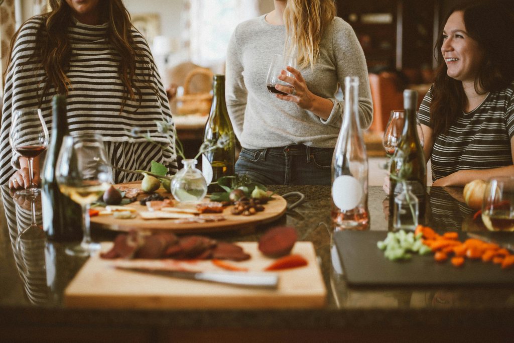 Holiday gathering with three women talking among grazing platters and wine