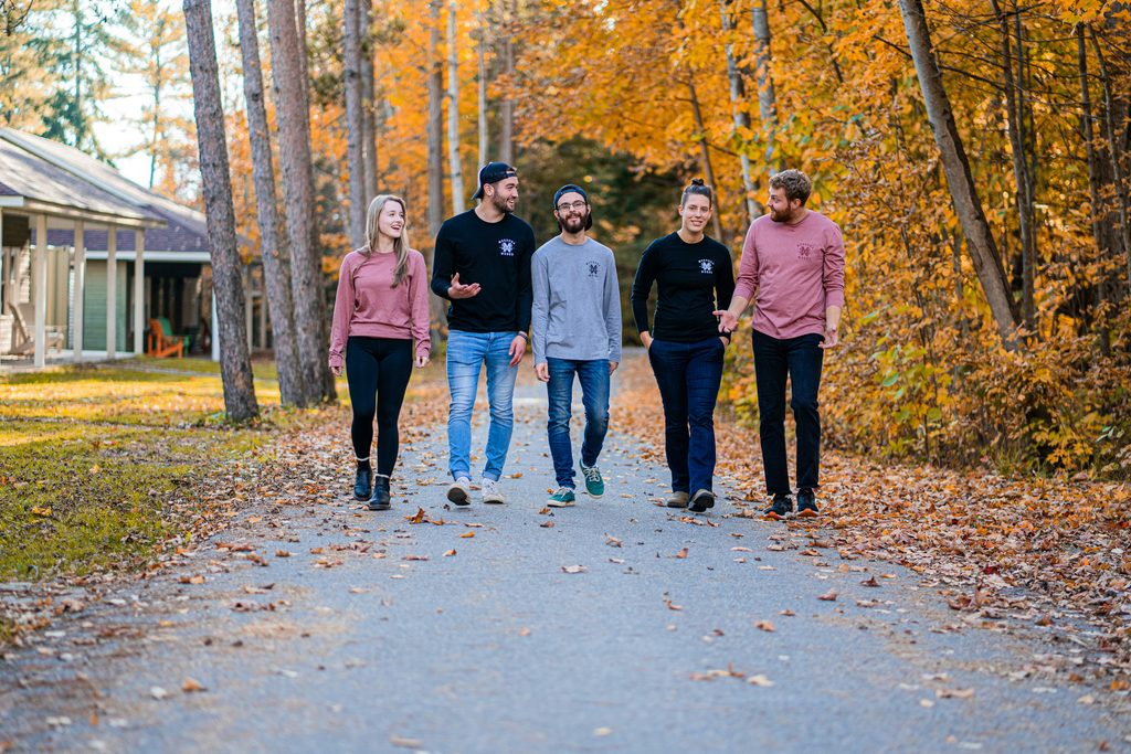 Group of friends walking down a road lined with fall foliage